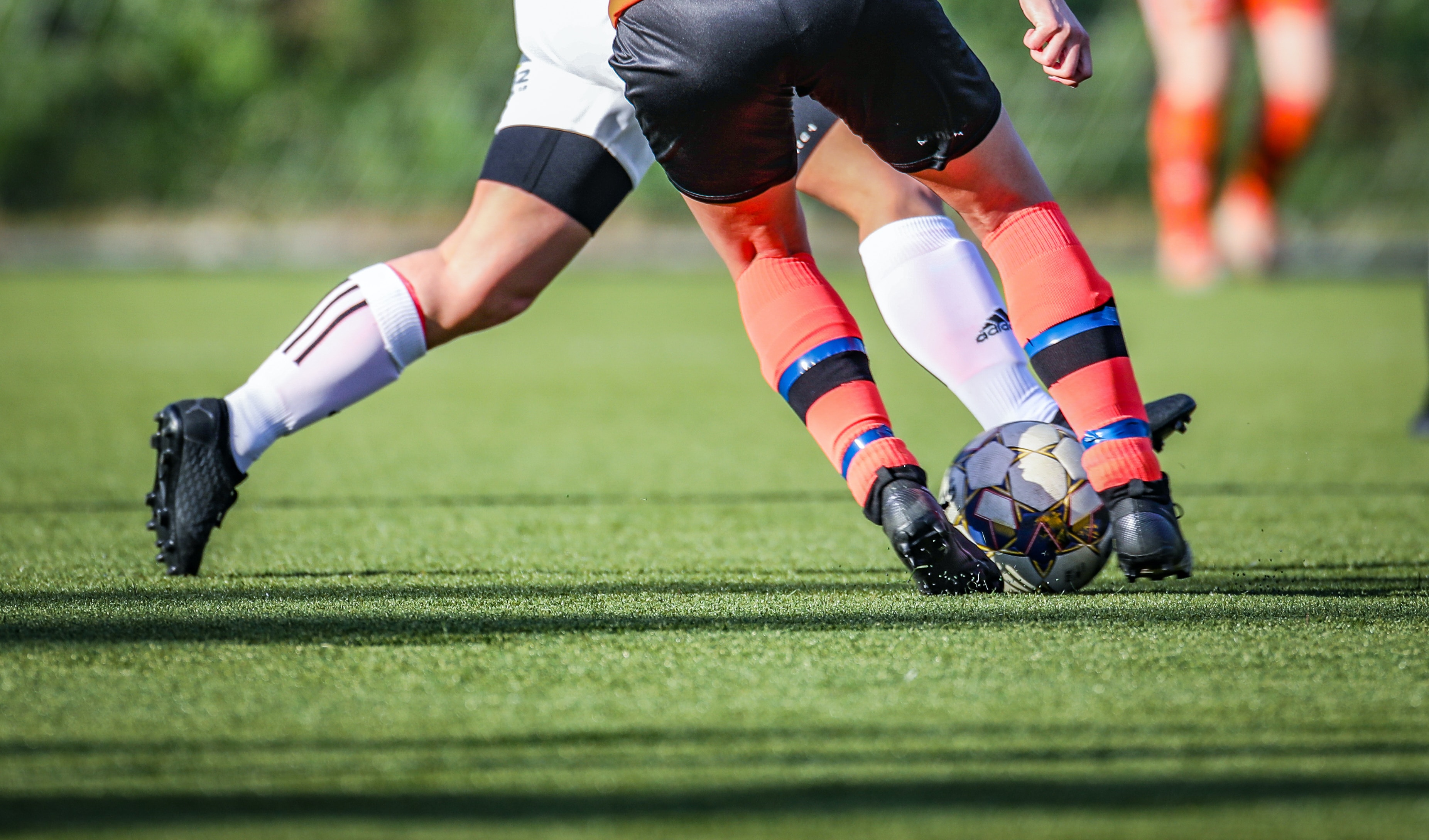 Legs of two footballers fighting for a ball on artificial turf