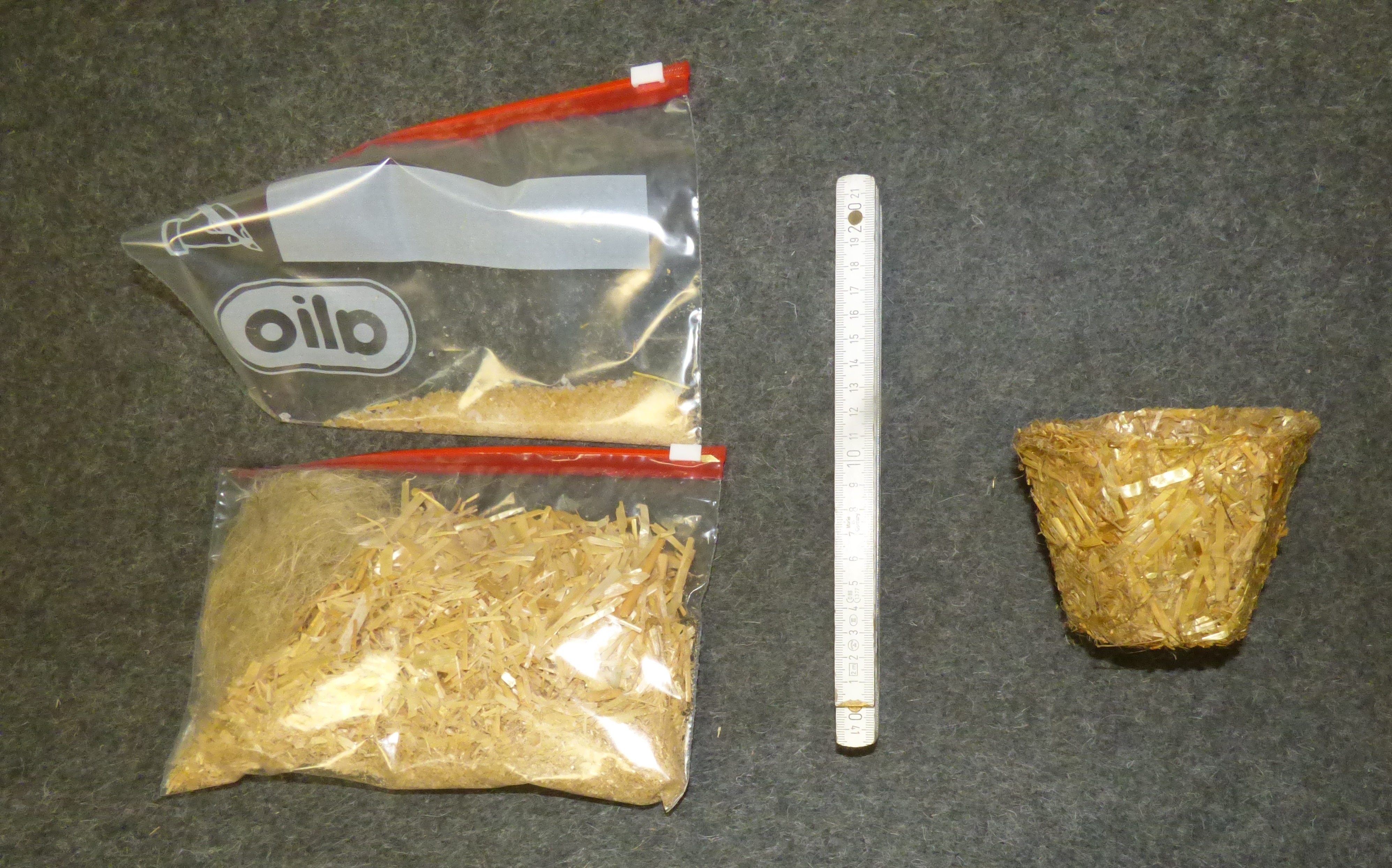 Two plastic bags filled with plant fibres and binder, a ruler for size estimation, and a plant pot