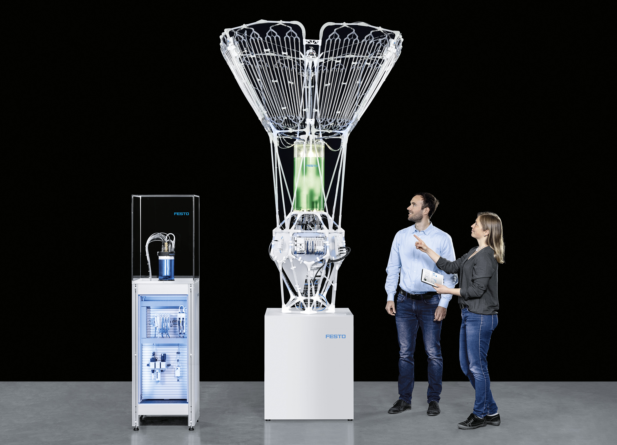 Two researchers and the bioreactor and separate control unit against a black background