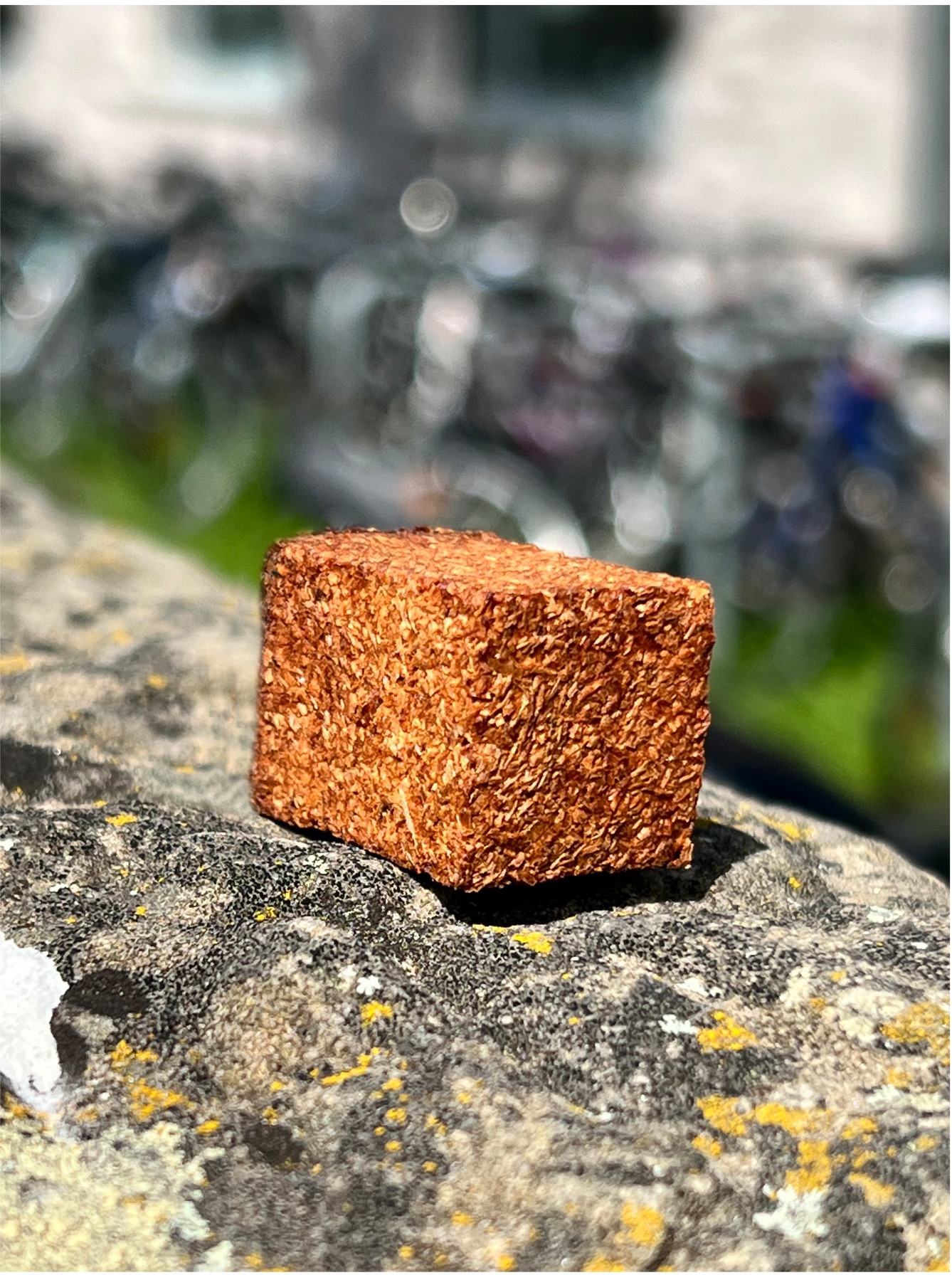 A brown, coarse piece of biocomposite on a stone wall