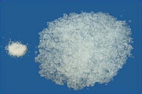 The picture shows the liquid absorbent filler in nappies as well as two piles of a white powder. On the left is a small pile (dry state of the superabsorbent). On the right is a pile about 7 times larger (state after absorption of water).