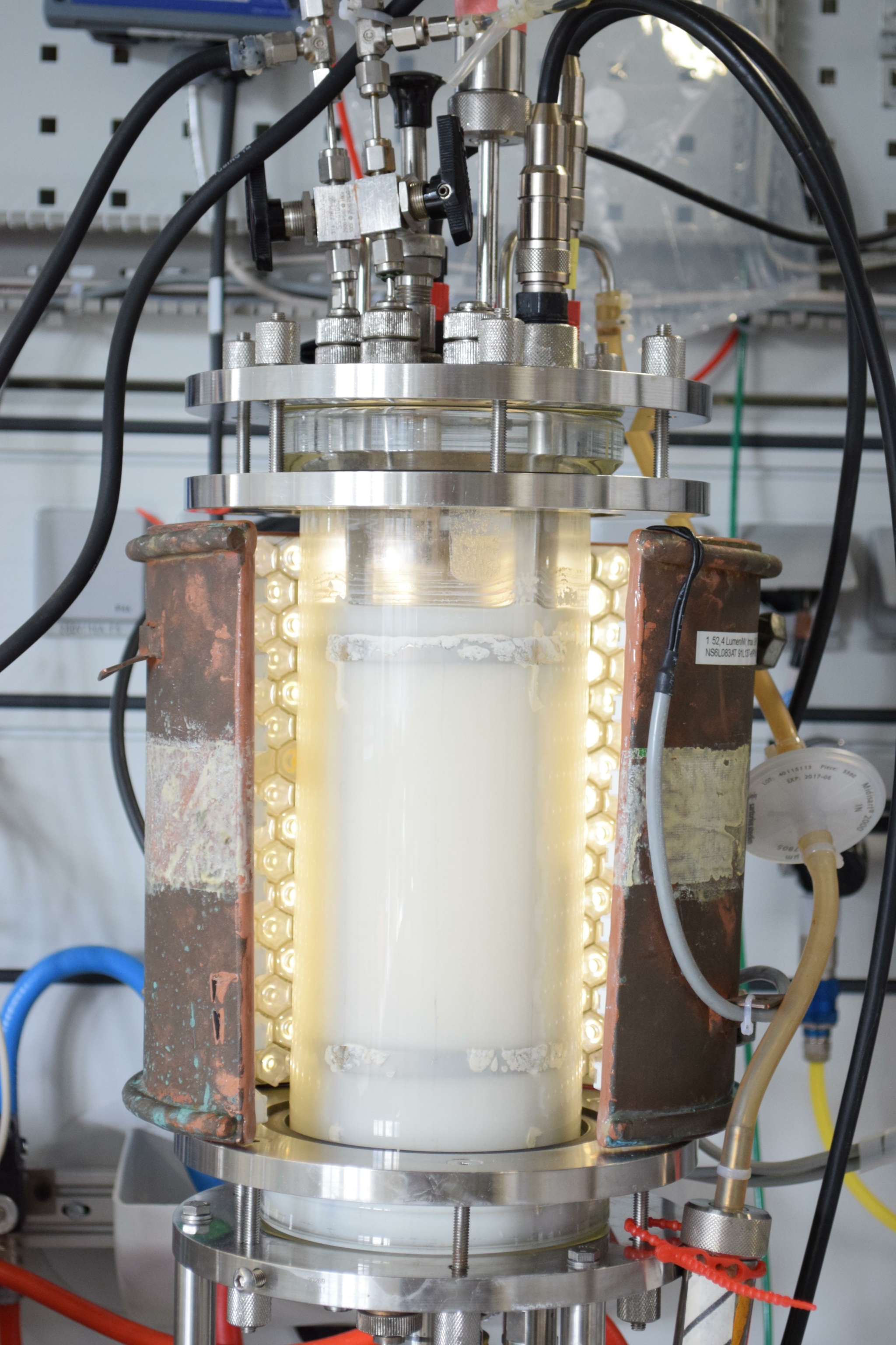 The photo shows a reactor surrounded by an enclosure of light-emitting diodes.