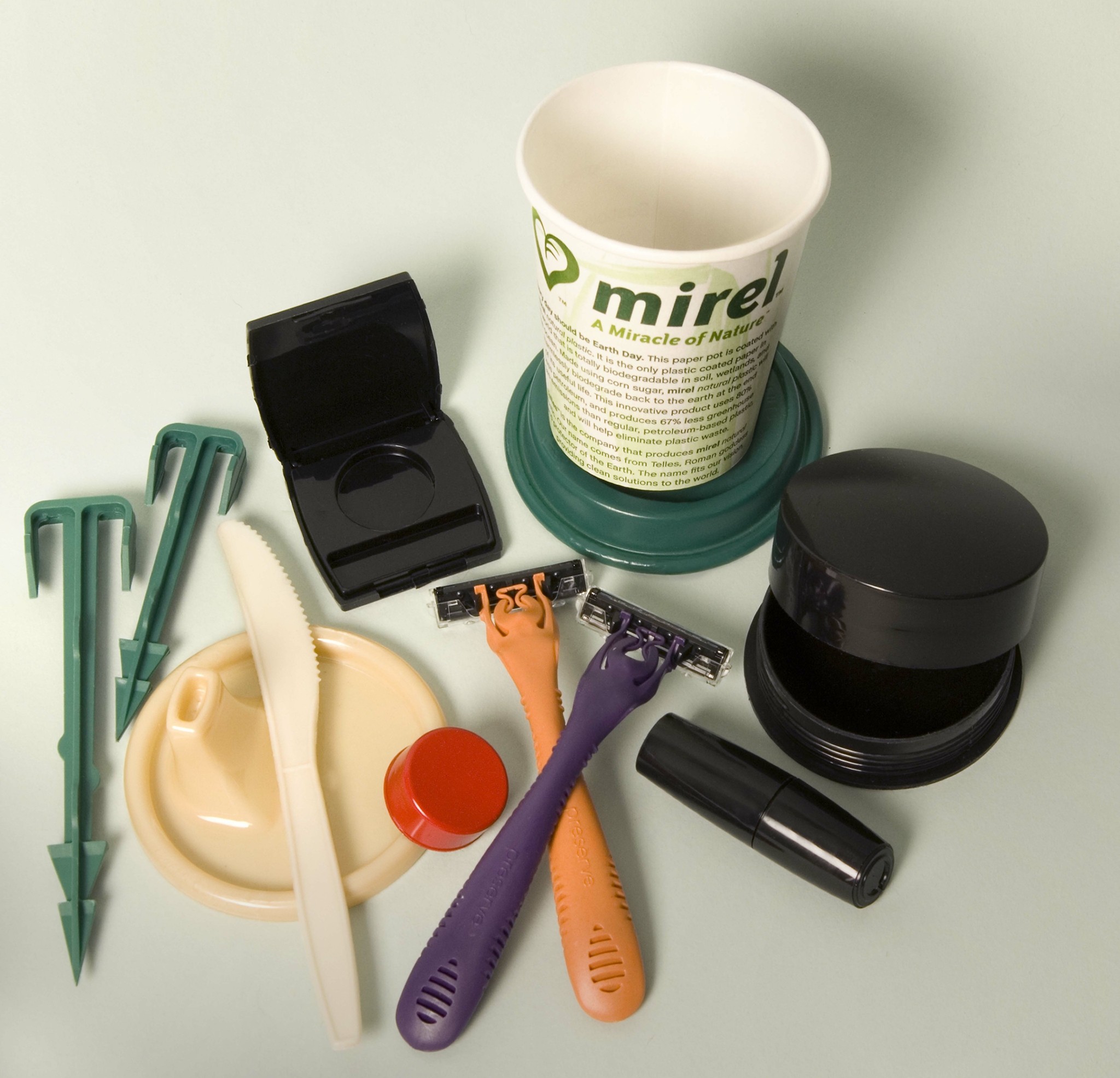 Zu sehen sind mehrere Produkte aus Kunststoff: Zeltheringe, ein Schnabeltassendeckel, ein kleiner roter Flaschendeckel, ein Messer, eine Kosmetikdose, zwei Nassrasierer, ein Becher, eine Lippenstiftdose und eine Puderdose.