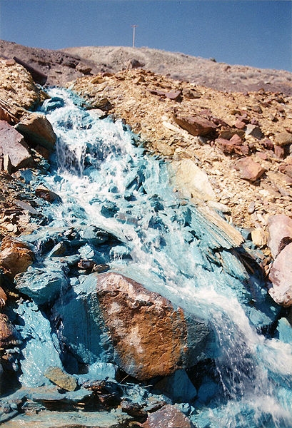 Stream stained turqouise-blue as it emerges from spoilings.