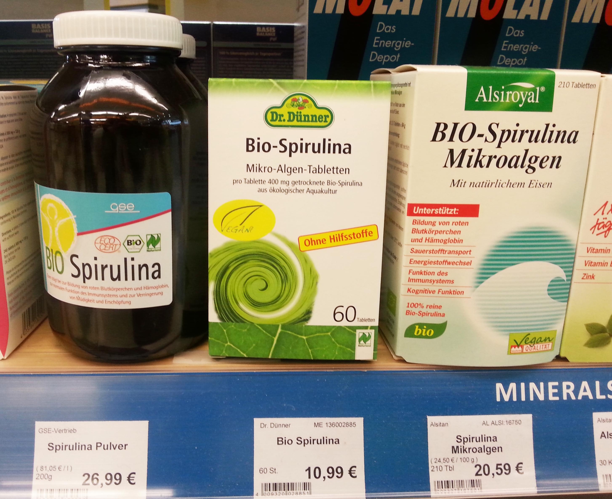 The photo shows Spirulina products in a supermarket shelf.