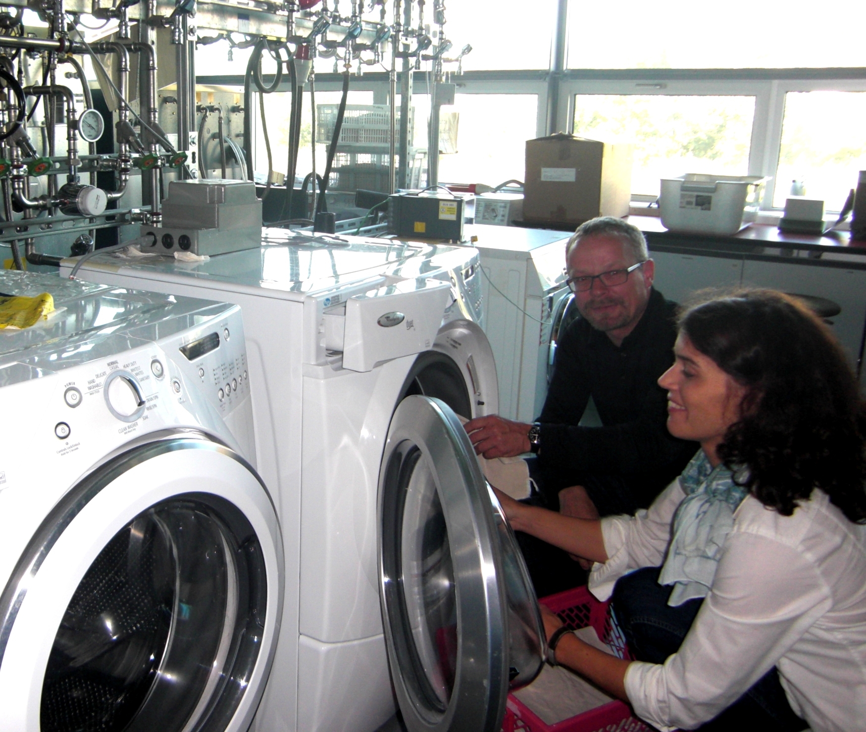 The photo shows Daniel Fäh, Managing Director Empa Testmaterials AG, and his colleague Caroline Amberg, project manager microbiology, in the laundry room loading test fabrics into the washing machine.