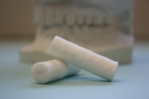 Two coated cotton dental rolls are shown.