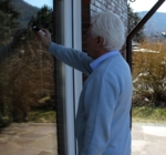 Ein Mann steht vor einer spiegelnden Fensterscheibe und wendet den Vogelschutzstift birdpen an