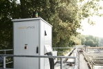 White technical cabinet with four hoses placed at the edge of a wastewater treatment plant.