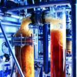 Photo of the extraction procedure used to produce medicinal extracts. Two tube-shaped containers that are connected with each other by other tubes contain a brown liquid. Dr. Willmar Schwabe GmbH & Co. KG uses state-of-the-art methods to produce extracts for herbal medicines.